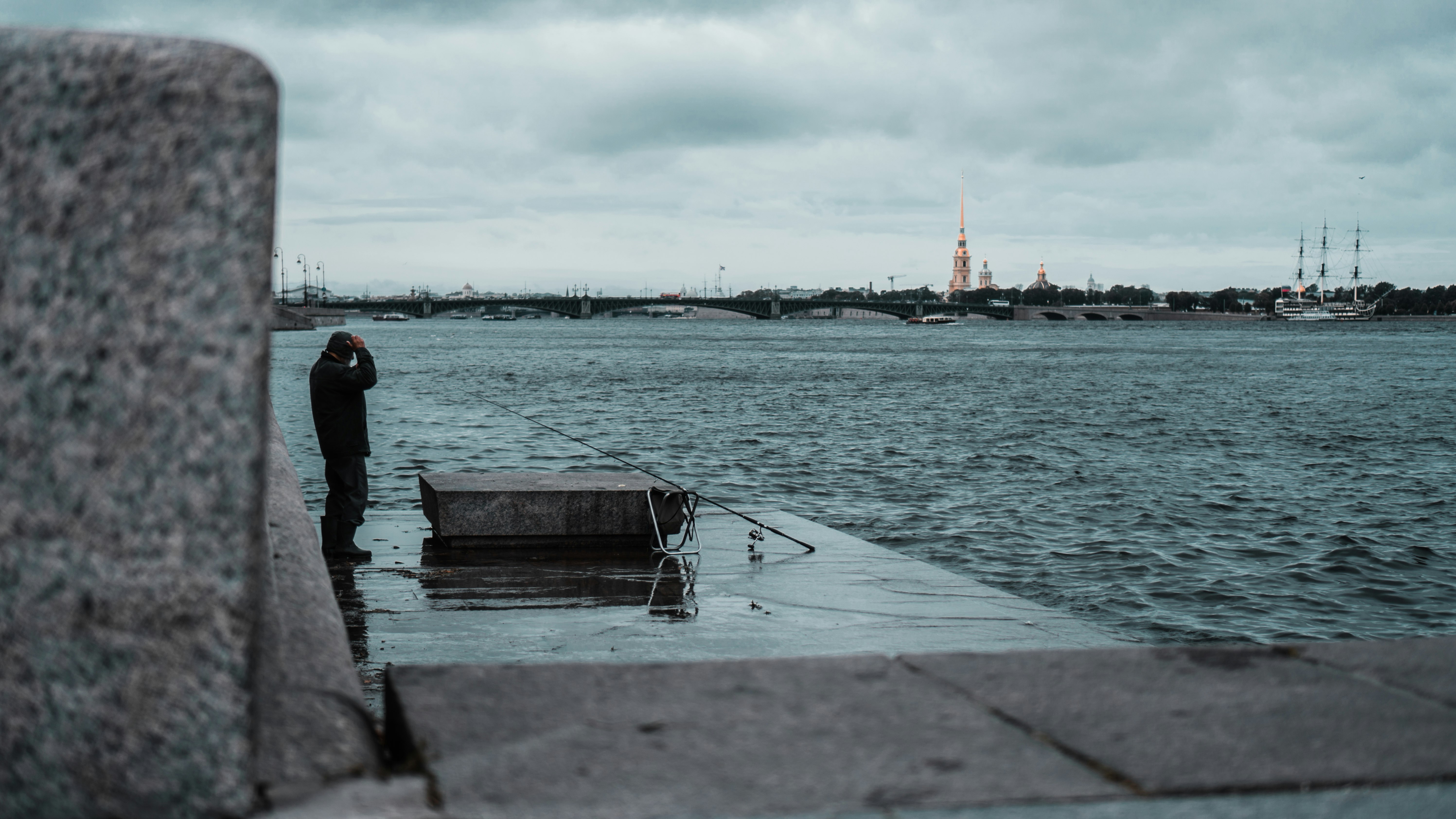 man in black jacket sitting on dock during daytime
